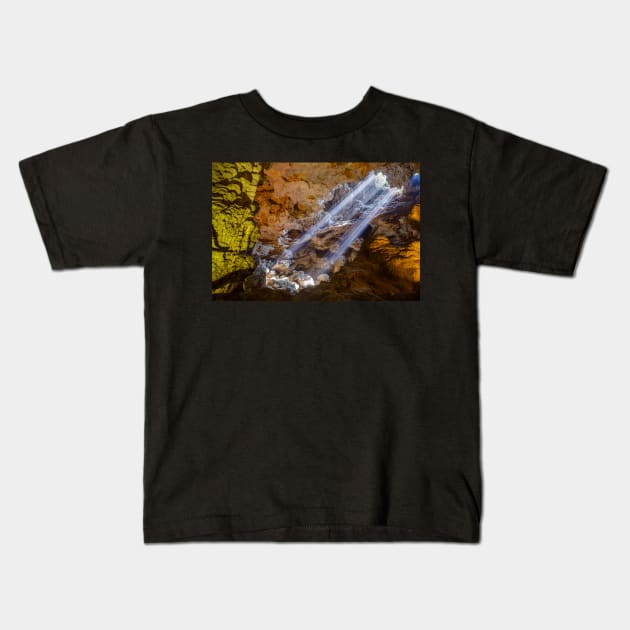 Sun rays shine through ceiling hole in Dau Go cave in Halong Bay, Vietnam Kids T-Shirt by auradius